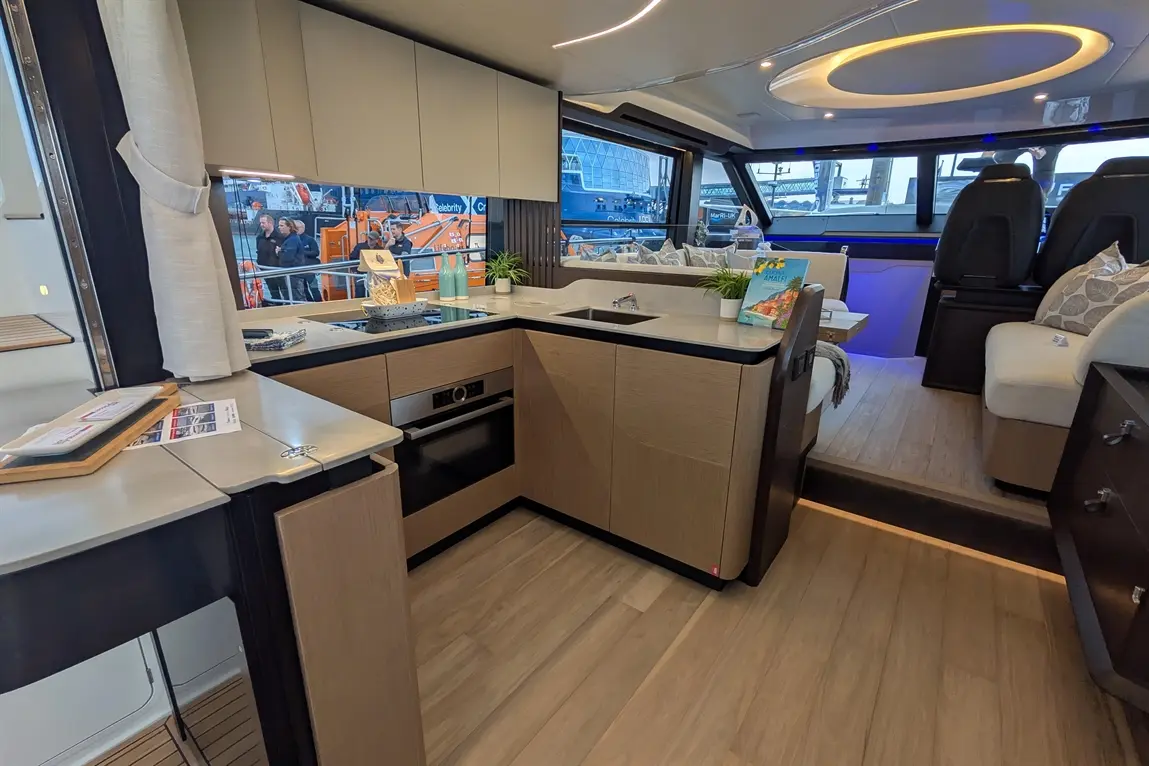 Modern yacht interior featuring a kitchen space with sleek cabinetry, an island, and scenic views through large windows.
